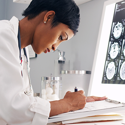 A female doctor taking notes during an online consultation