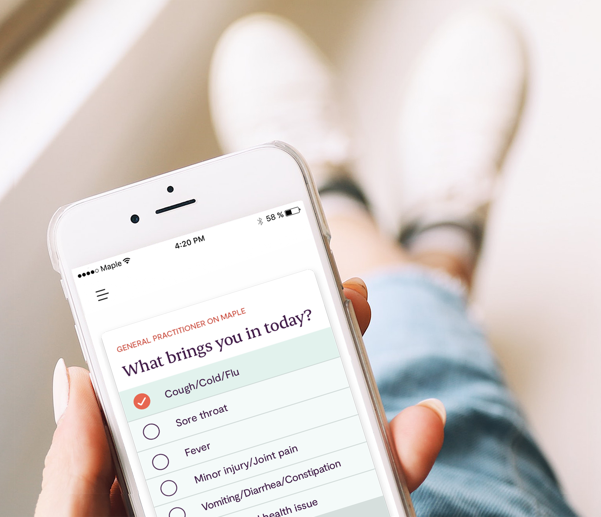 Person holding a phone with a list of symptoms appearing on the Maple app