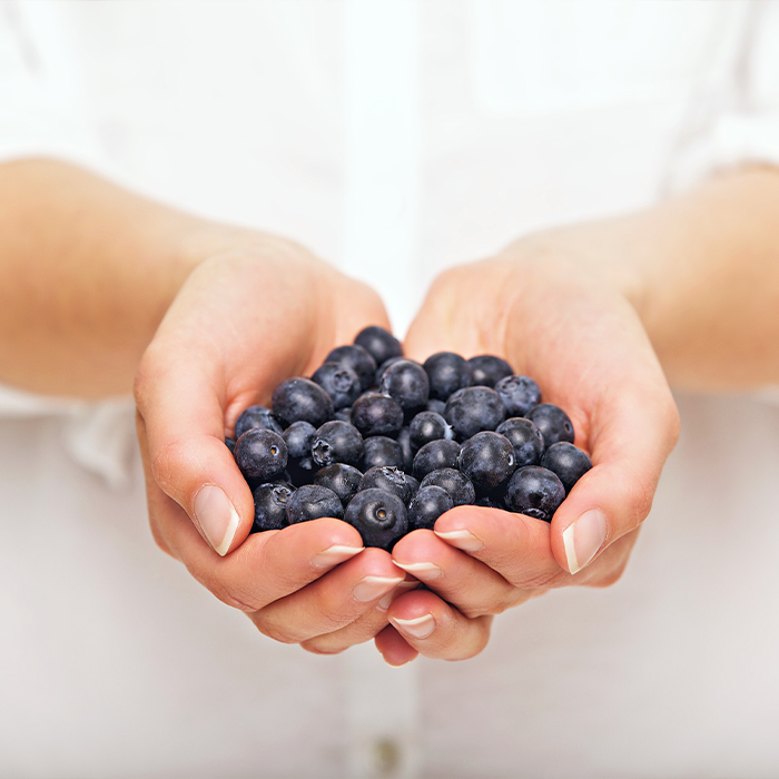 A woman holding blueberries with her hands