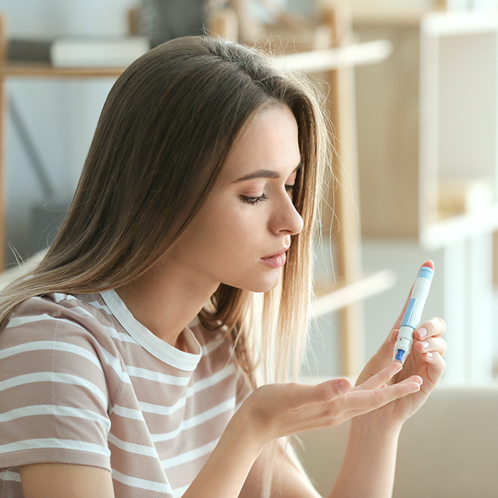 A woman checking her blood sugar levels by performing an at-home diabetes test