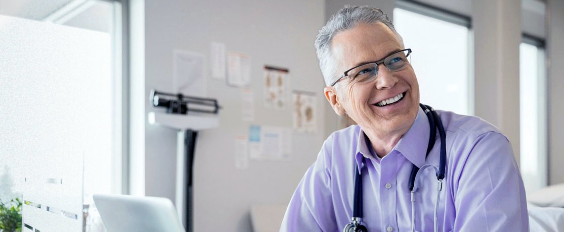 A male doctor smiling getting ready to take an online consultation