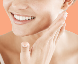 A woman smiling touching her face