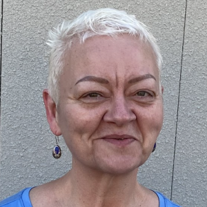 Headshot of Cassandra Brade, taken against a textured white wall