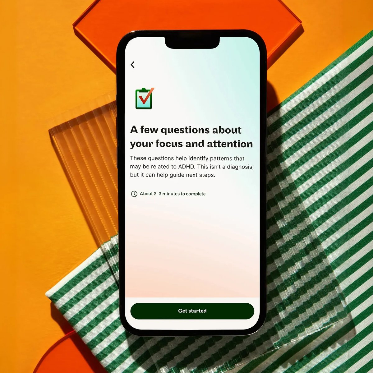 A smart phone laid flat on a colorful table, showing an early step in the Maple onboarding flow on a smart phone. A few questions about your focus and attention.