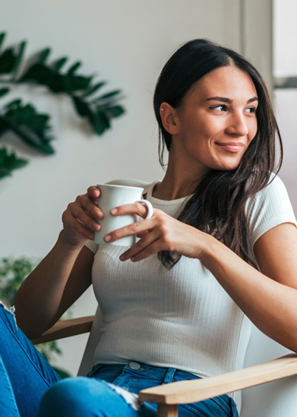 A young woman holding a cup of coffee waiting for her prescription to be delivered to her home