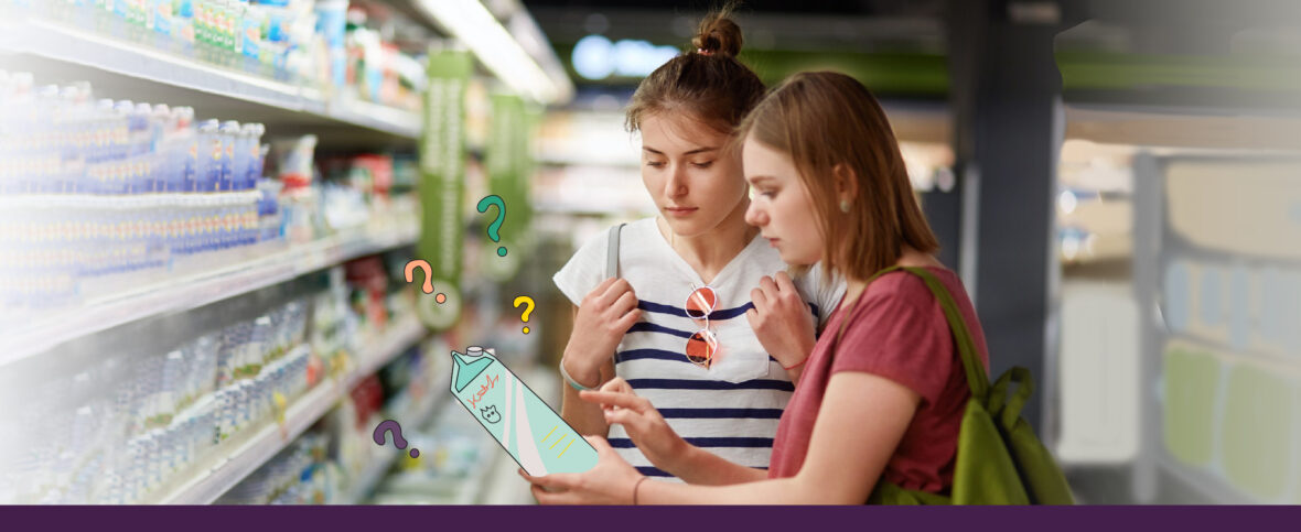 Two women examining a carton of milk, wondering if milk or dairy causes acne.