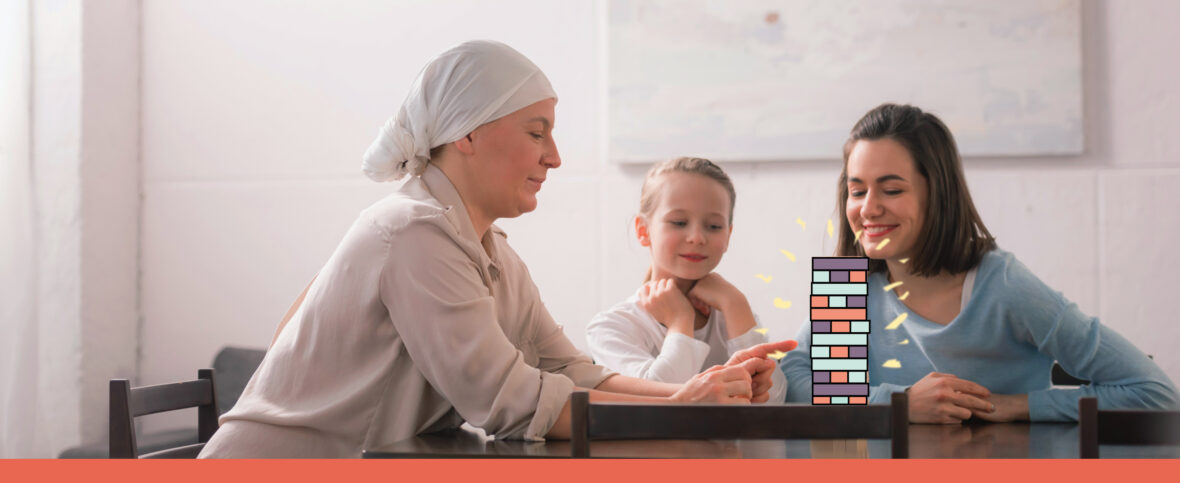 Woman and child playing jenga with a woman who is going through breast cancer treatment, as shown my the cloth covering her hair.