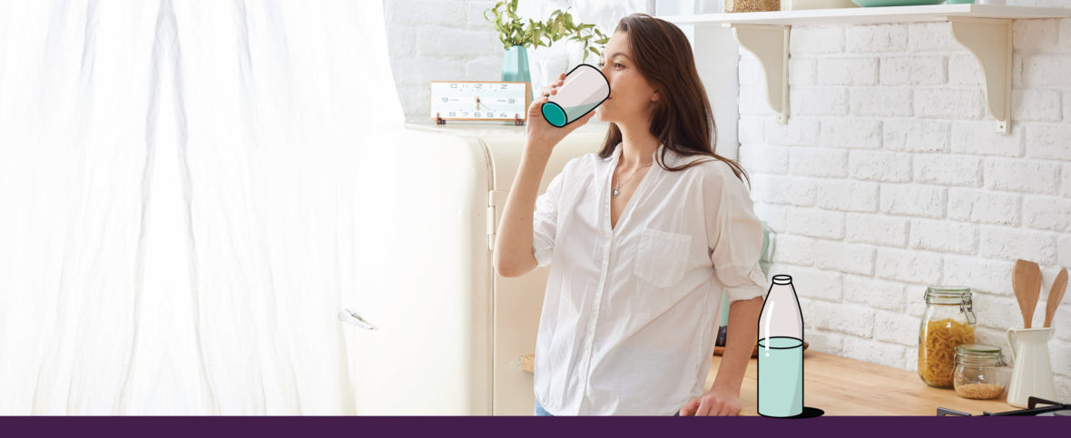 A woman drinking a glass of water, as staying hydrated helps with intermittent fasting.
