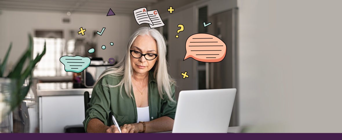 Woman sitting in front of a computer, writing with a paper and pen as she does a cognitive assessment.