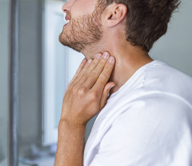 A man doing an at-home self-exam known as the thyroid neck check