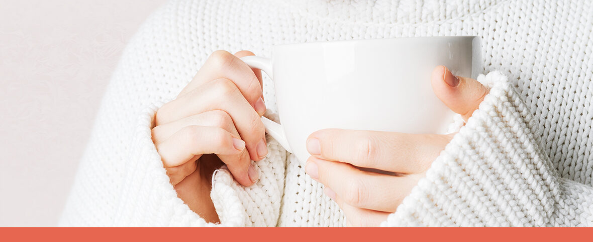 Close-up of a person holding a mug to help prevent dehydration in the cold weather.