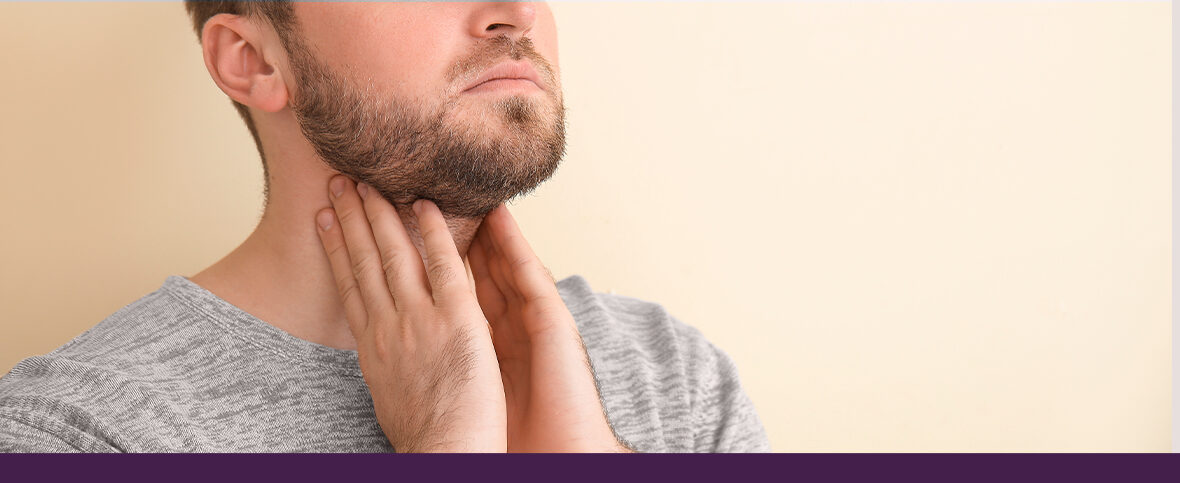 Male experiencing hypothyroidism symptoms in winter, holding his neck with both hands.