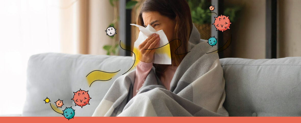 Woman with pneumonia symptoms wrapped in a blanket on the couch, holding a tissue in front of her nose. Illustrated viruses surround her.