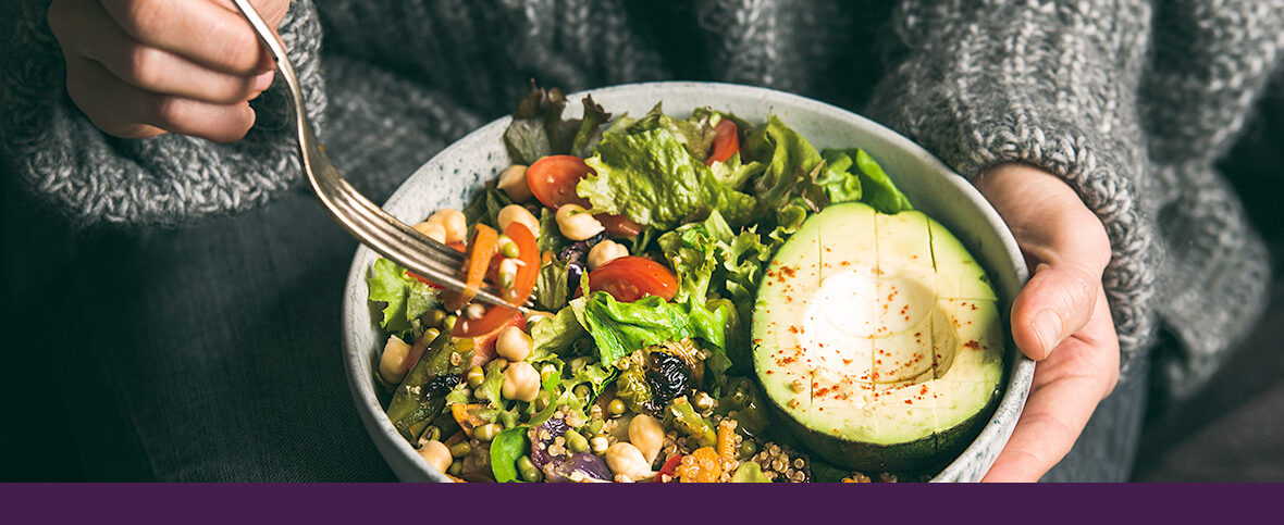 Person following a PCOS diet plan holding a bowl filled with salad and half an avocado.