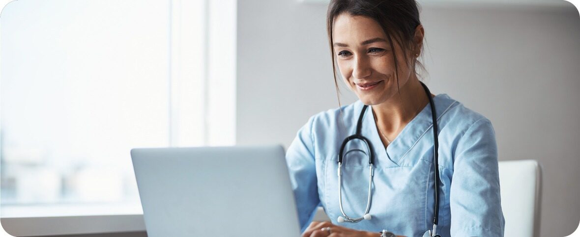 healthcare provider sitting at table with a laptop open